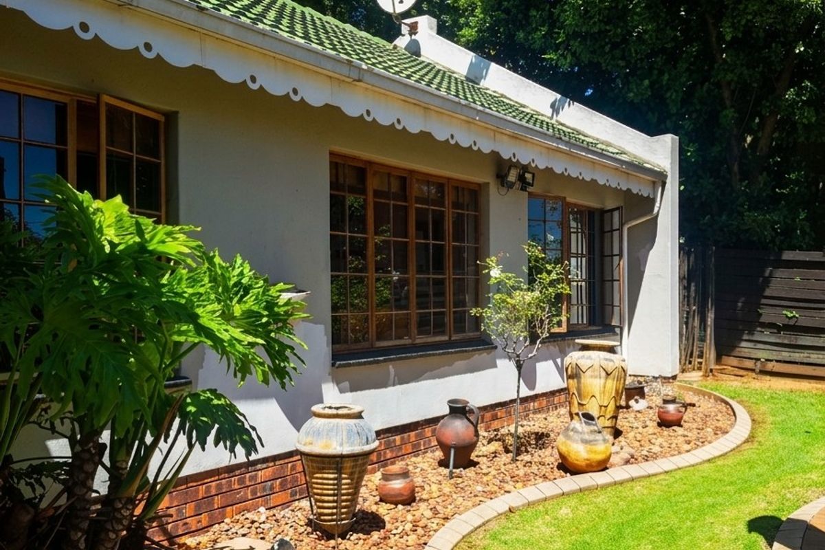 A well-maintained rear exterior view featuring a tiled roof, decorative eaves, timber-framed windows, and a landscaped garden with stone pathways and brick edging.