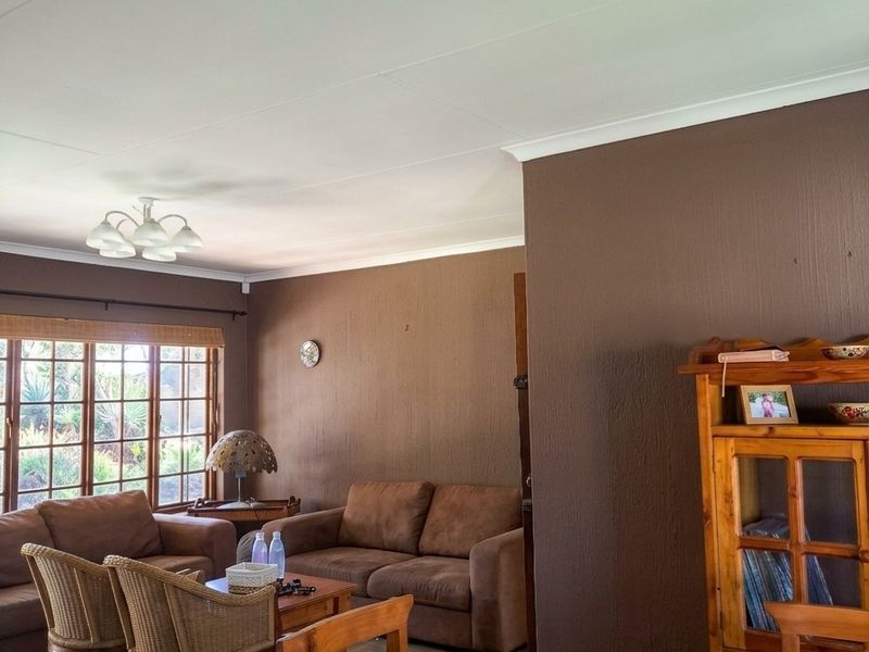 A living room featuring tiled flooring, coved ceilings, and a large window that provides natural light.