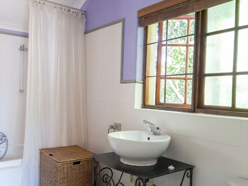 A dated bathroom featuring a vessel sink, bathtub with shower curtain, and patterned floor tiles, requiring cosmetic updates to modernize the space.