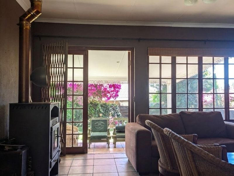 Living room featuring a freestanding fireplace with flue, tiled flooring, and large multi-pane windows and doors providing access to the garden.