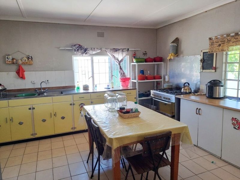 A functional kitchen featuring dated yellow cabinetry, a gas stove, tiled flooring, and a stainless steel sink with window views.