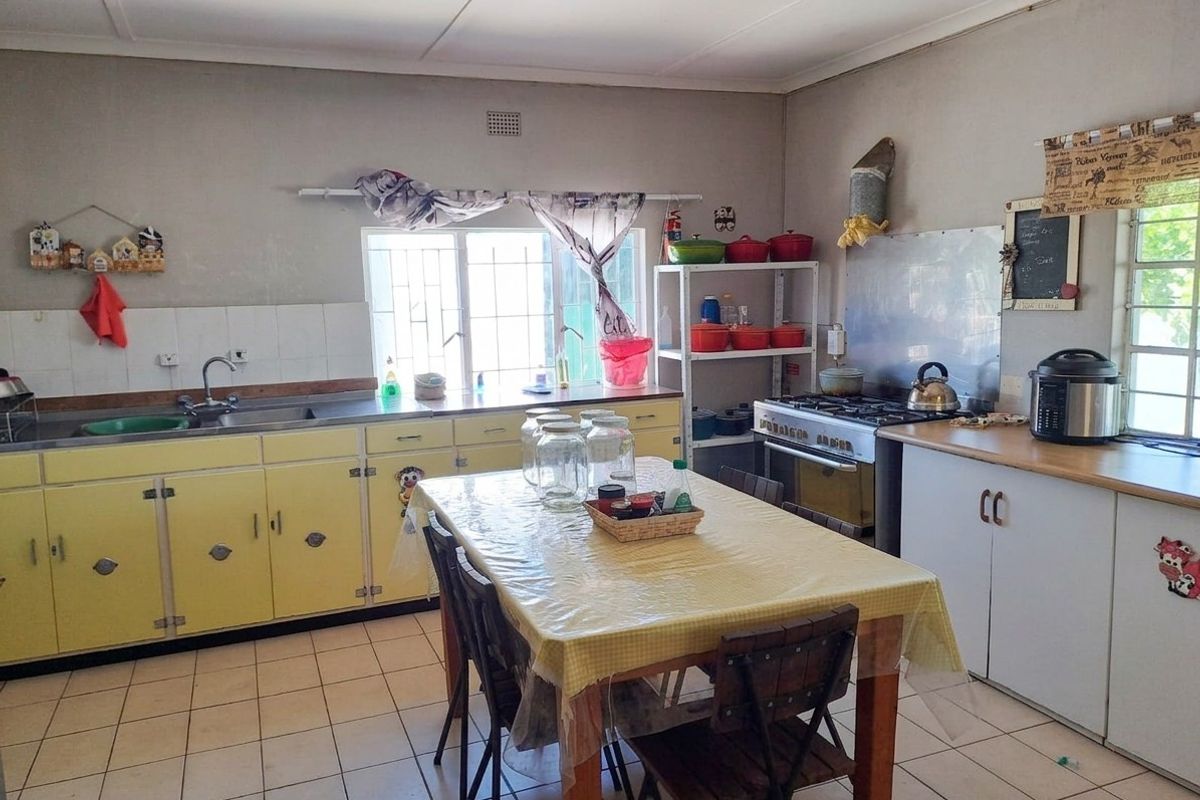 A functional kitchen featuring dated yellow cabinetry, a gas stove, tiled flooring, and a stainless steel sink with window views.