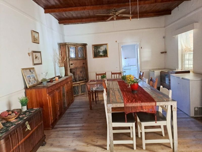 Spacious dining room featuring rustic timber flooring and exposed wooden ceiling beams, offering a warm and traditional atmosphere.
