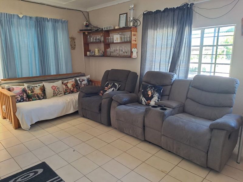 A living room area featuring tiled flooring and built-in wall shelving, currently showing signs of wear and exposed electrical wiring.