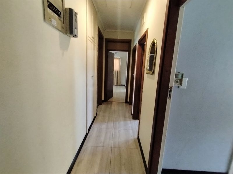 A functional hallway featuring tiled flooring, built-in storage cupboards, and access to multiple rooms.
