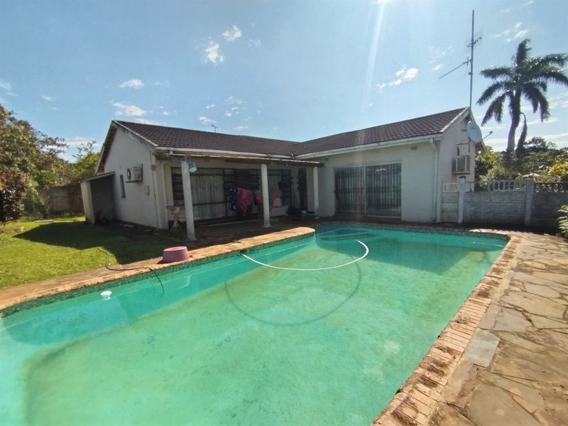 Rear exterior view featuring a swimming pool, paved patio area, and direct access to the home via sliding doors.