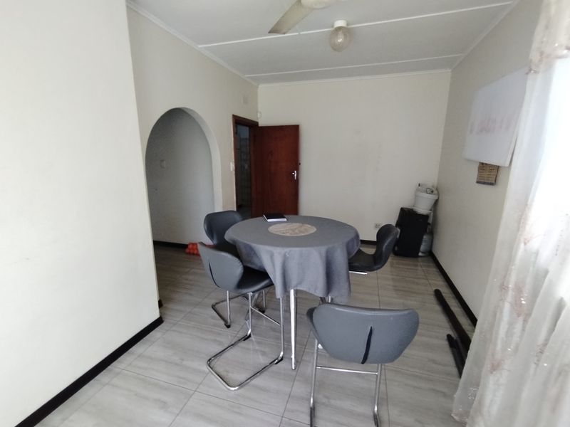 A functional dining area featuring tiled flooring, an arched entryway, and a ceiling fan, offering a neutral canvas for potential interior updates.