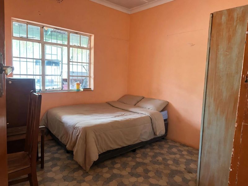 A bedroom featuring tiled flooring and security bars on the window, currently finished with peach-toned wall paint.