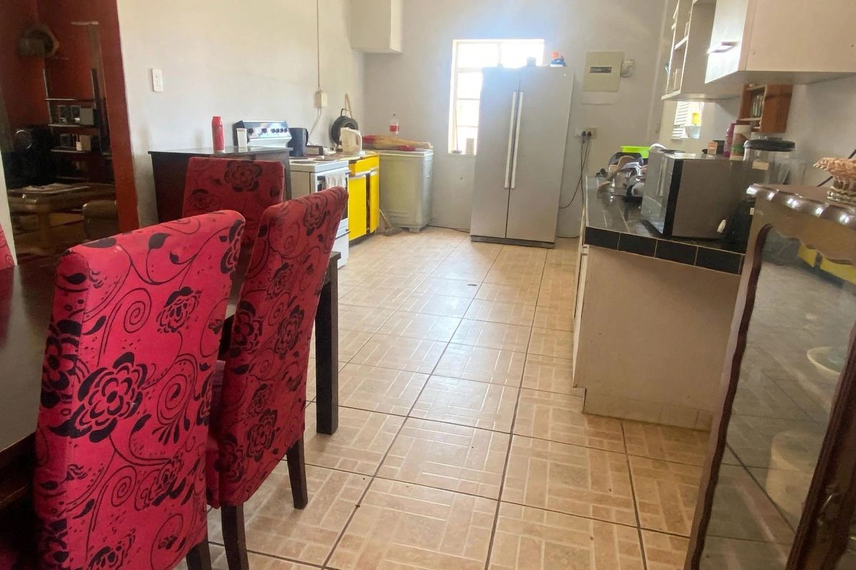 A functional kitchen space featuring tiled flooring and countertops with built-in cabinetry, offering potential for modernization and aesthetic updates.