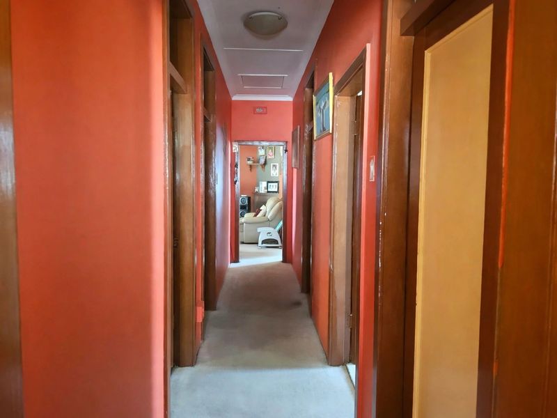 A long residential hallway featuring wooden door frames and carpeted flooring, providing access to multiple rooms within the home.