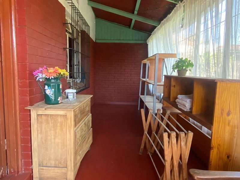 A covered patio area featuring exposed brick walls, security bars, and a sloped ceiling, offering a functional outdoor space with potential for modernization.