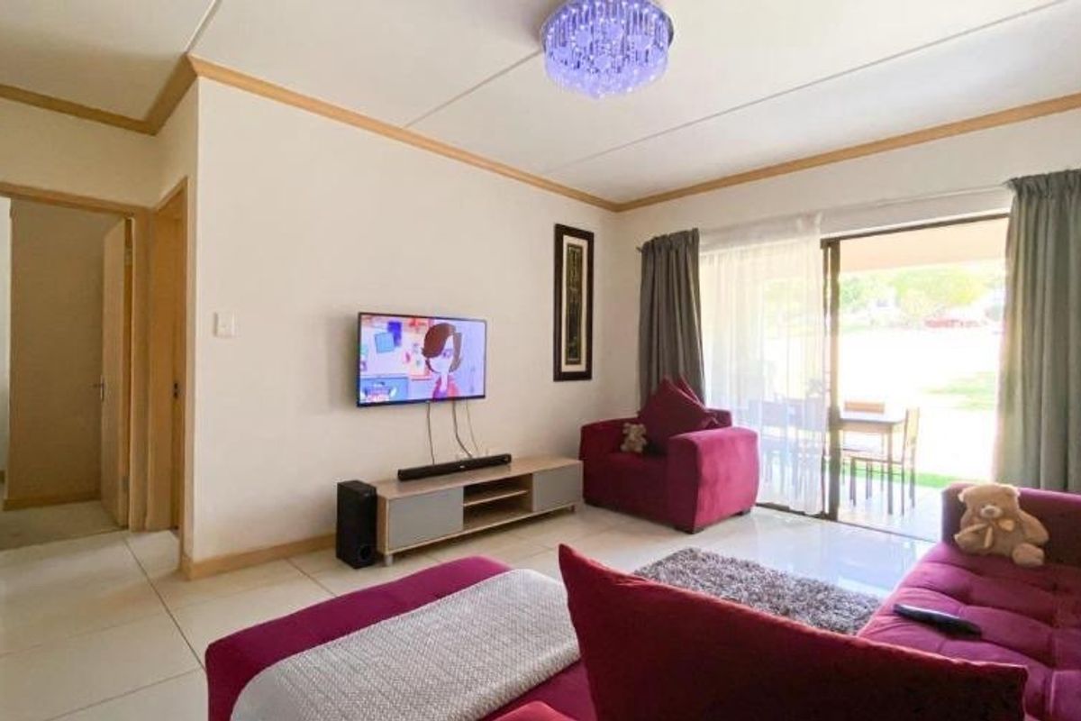 A bright living room featuring tiled flooring and a sliding glass door that provides access to the outdoor patio area.