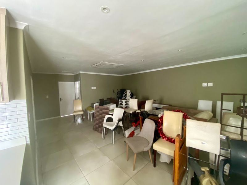 Spacious open-plan living area featuring neutral tiled flooring, recessed downlighting, and integrated ducted air conditioning, offering a versatile layout for various living arrangements.