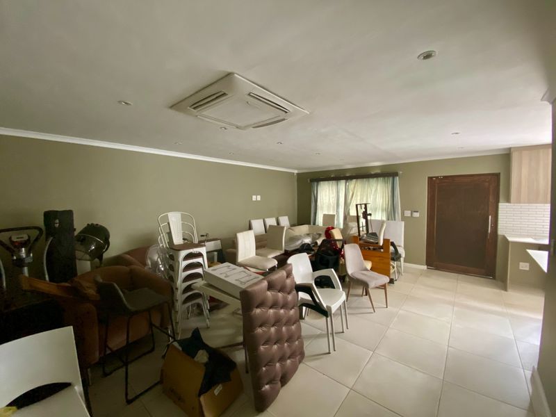 Spacious open-plan living area featuring tiled flooring, recessed lighting, and integrated ducted air conditioning, seamlessly connecting to a kitchen with modern cabinetry.