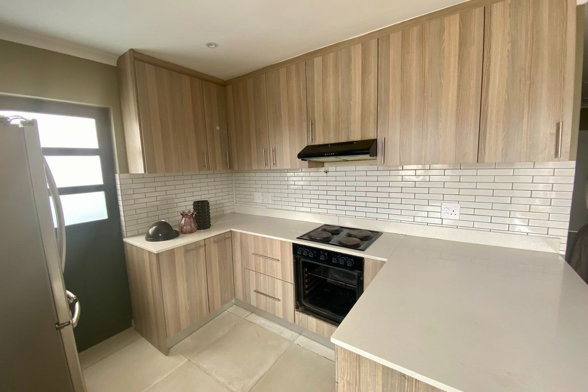 Modern kitchen featuring wood-look cabinetry, stone countertops, subway tile backsplash, and integrated electric cooking appliances.