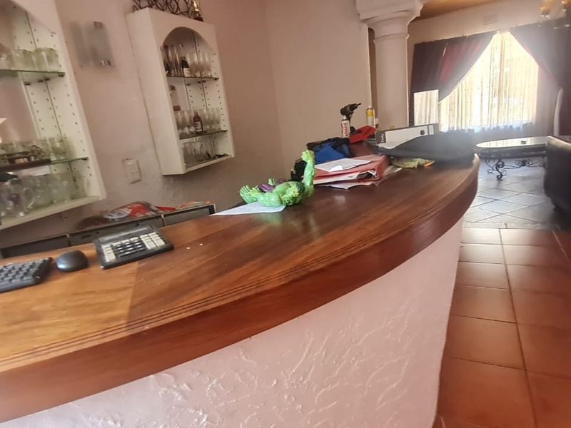 A built-in bar area featuring a wooden counter, integrated shelving, and tiled flooring, providing a dedicated space for entertainment.