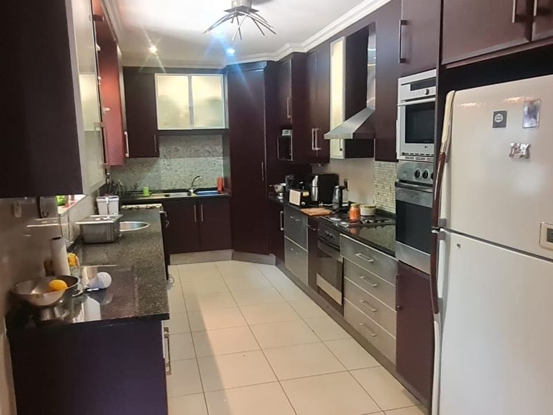 A functional kitchen featuring dark wood cabinetry, granite countertops, built-in appliances, and tiled flooring, offering a practical layout for daily cooking and preparation.