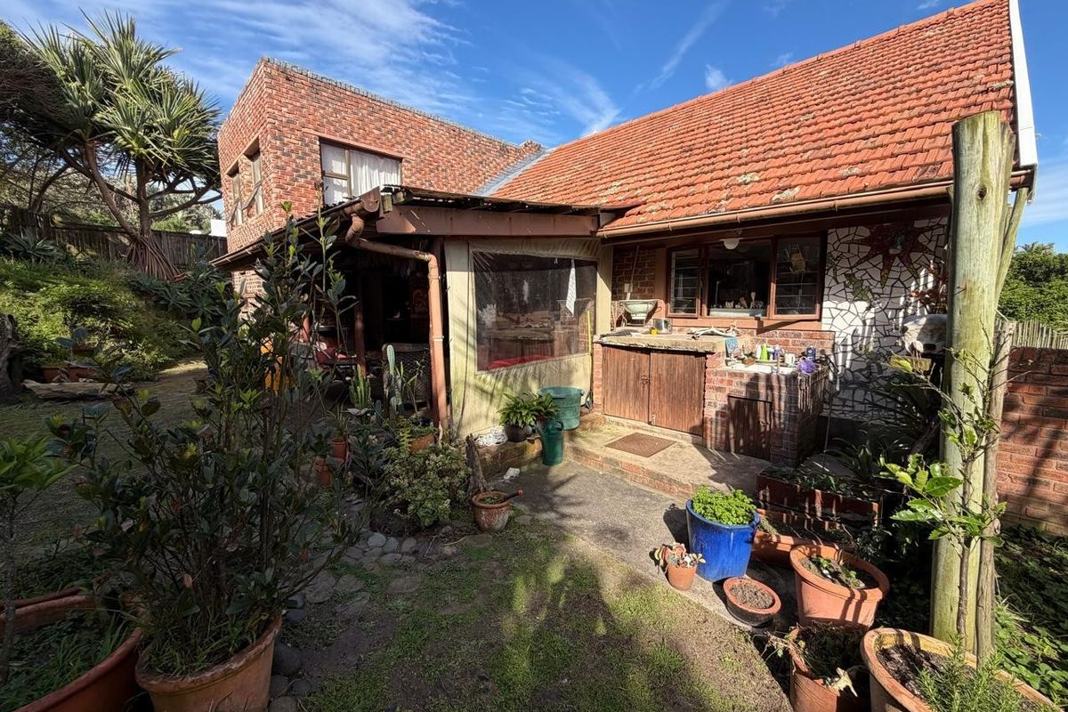 Rear view of the property featuring a brick facade, tiled roof, and a covered patio area with a built-in outdoor counter.