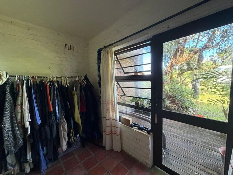 A bedroom featuring terracotta tile flooring, painted brick walls, and direct access to an outdoor deck through a glass panel door.