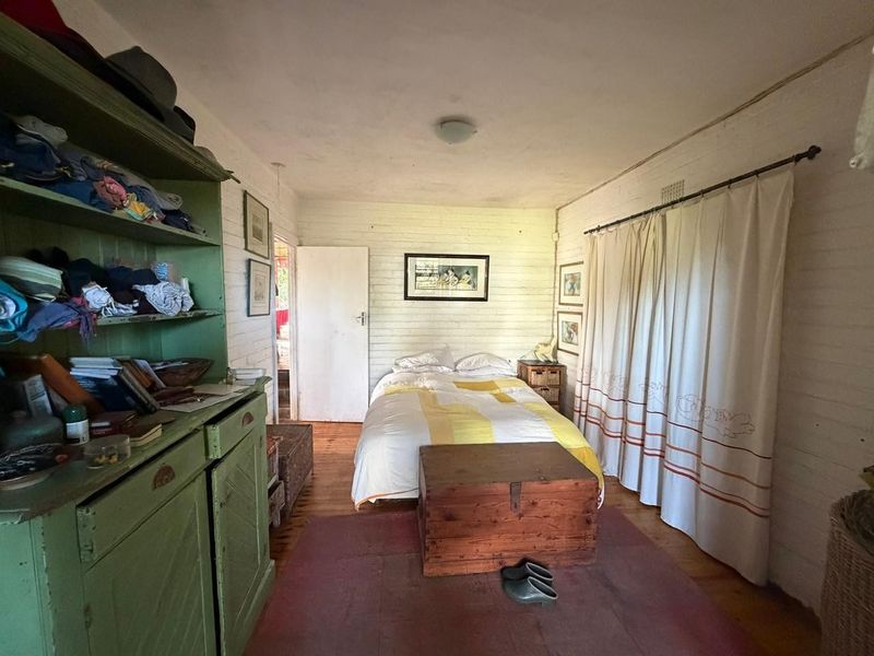 A bedroom featuring painted brick walls and timber flooring, offering a rustic aesthetic with potential for modernization.