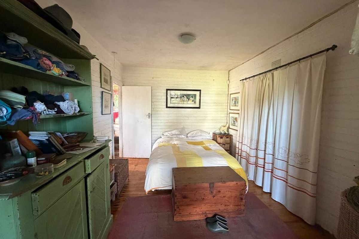 A bedroom featuring painted brick walls and timber flooring, offering a rustic aesthetic with potential for modernization.
