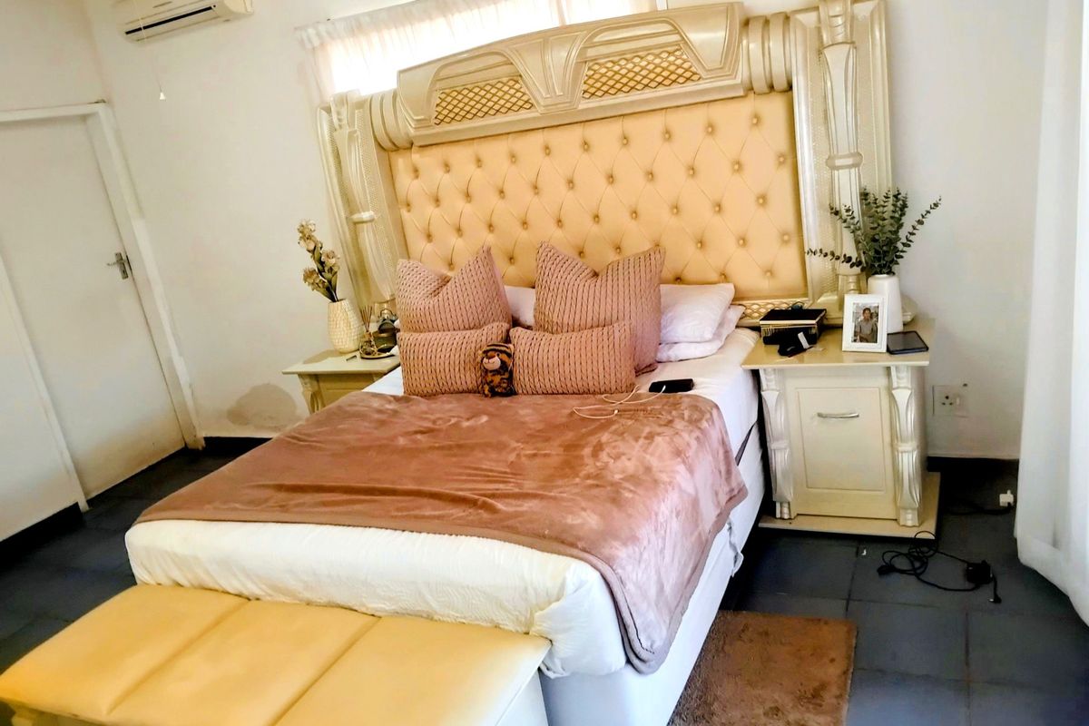 A bedroom featuring tiled flooring and a wall-mounted split-system air conditioner unit.