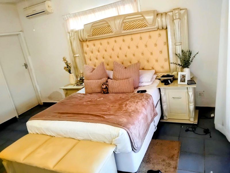 A bedroom featuring tiled flooring and a wall-mounted split-system air conditioner unit.