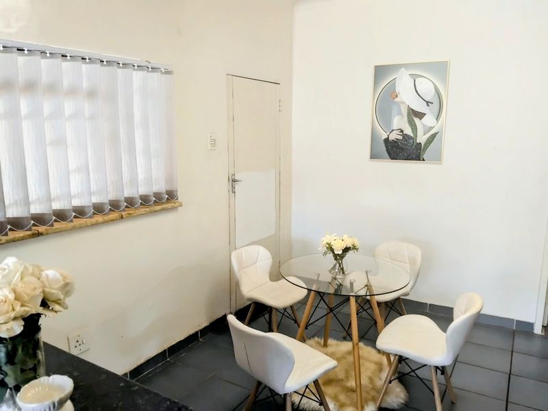 A bright dining area featuring tiled flooring, vertical window blinds, and neutral wall finishes, providing a clean and functional space for meals.