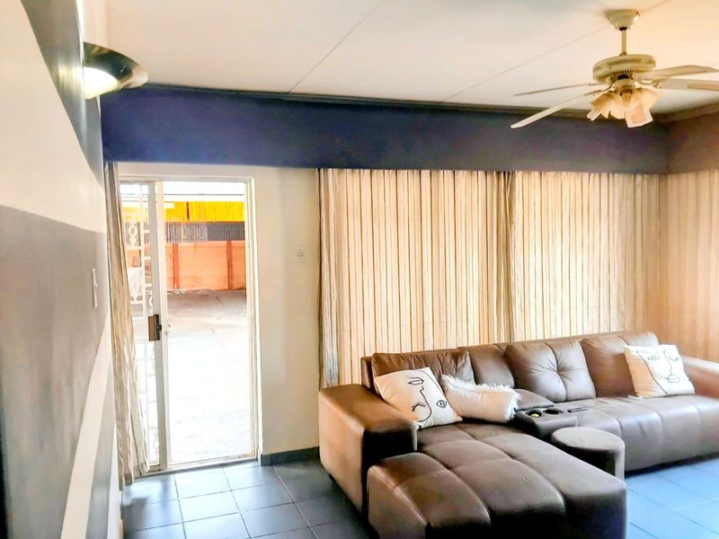A living room featuring tiled flooring, a ceiling fan, and a sliding glass door providing access to the exterior.