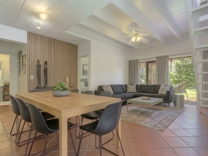 Spacious open-plan living and dining area featuring exposed beam ceilings, a decorative slatted timber wall, and direct access to the garden.