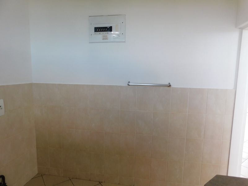 A functional utility area featuring tiled wall splashbacks, a wall-mounted electrical distribution board, and a metal towel rail.