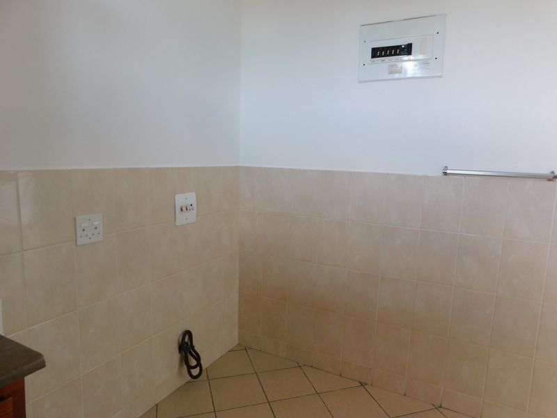 A functional laundry area featuring tiled walls and flooring, equipped with a distribution board and power outlets for appliance connectivity.