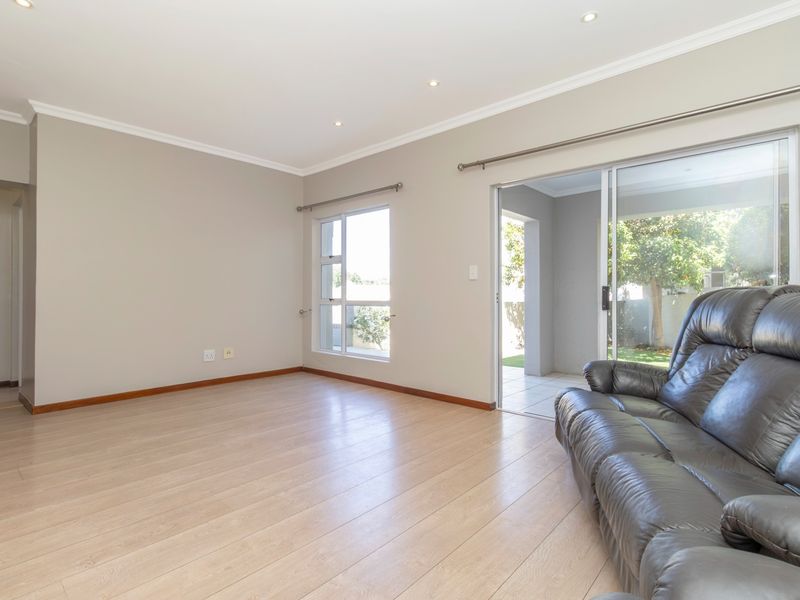 Bright living room featuring light laminate flooring, recessed downlights, and sliding glass doors providing direct access to the outdoor patio area.