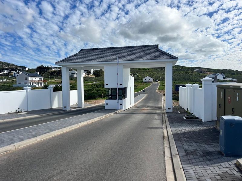 A modern, well-maintained security gatehouse entrance for a residential estate, featuring paved driveways and perimeter walling.