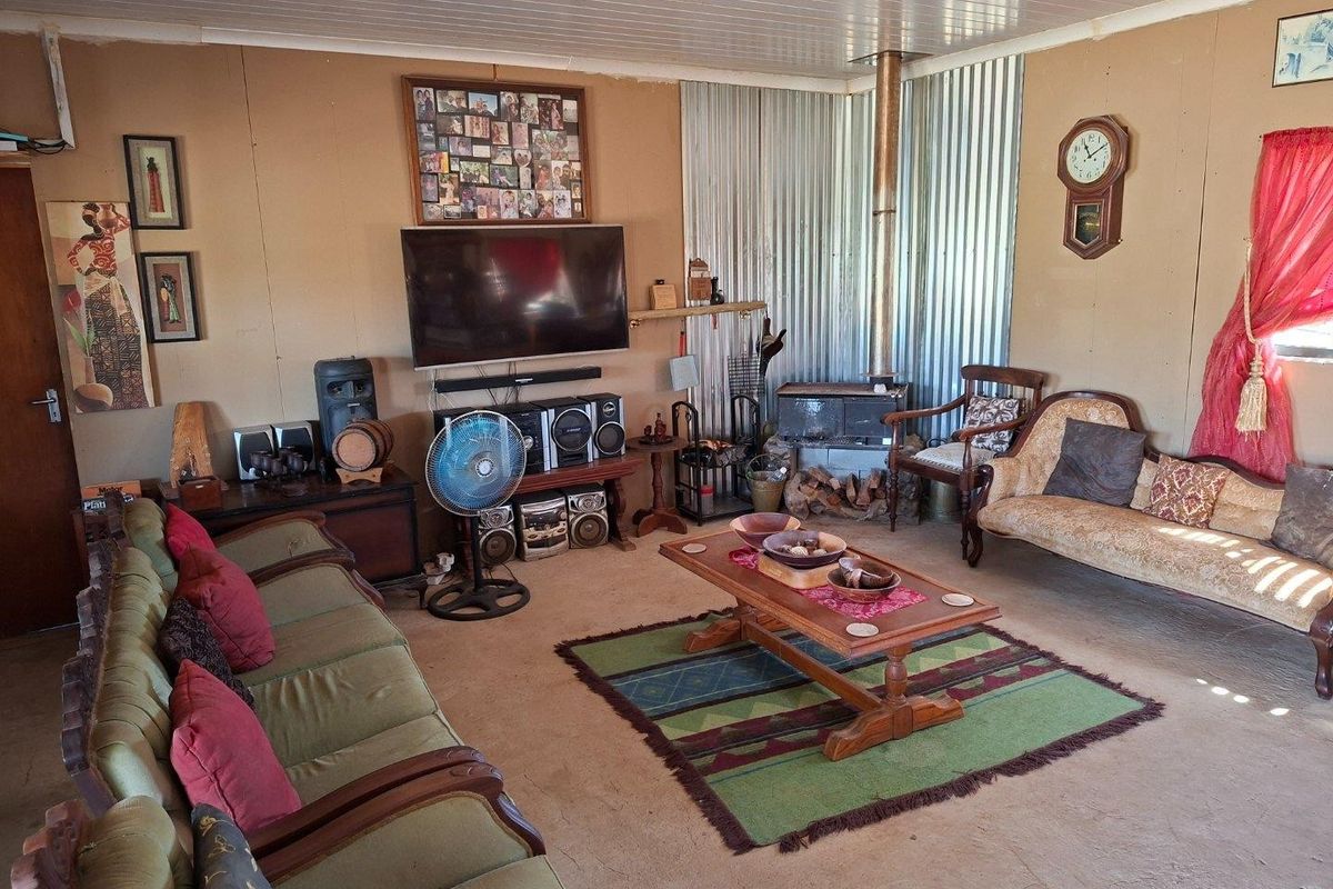 A rustic living room featuring a wood-burning stove, corrugated metal wall accents, and a tongue and groove ceiling.