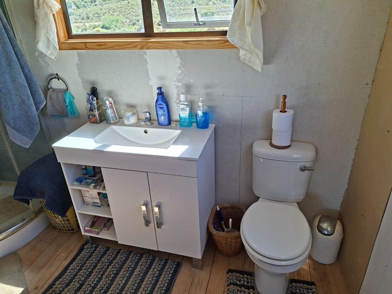 A functional bathroom featuring a vanity unit, toilet, and shower enclosure, currently requiring wall finishing and cosmetic updates to complete the space.
