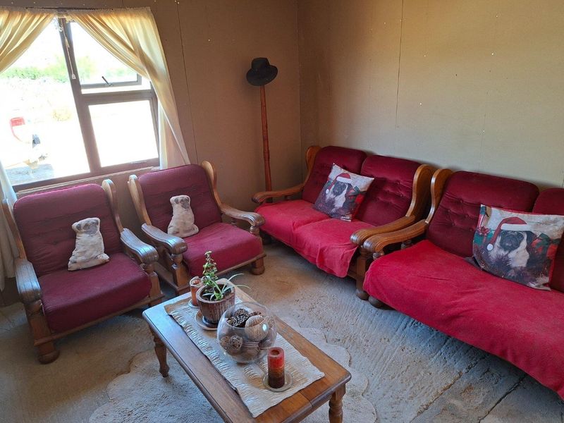 A living room area featuring basic wall finishes and an unfinished concrete floor, providing a blank canvas for potential renovation and interior updates.
