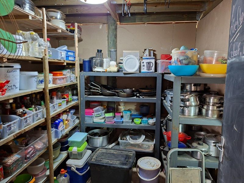 A functional storage and utility area featuring exposed timber framing and plywood walls, currently utilized for kitchenware and pantry storage.
