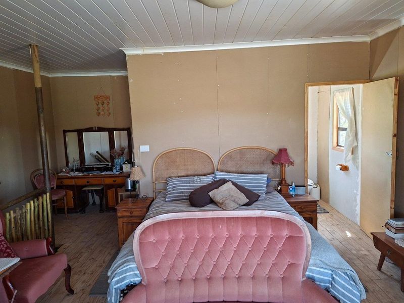 A rustic bedroom featuring timber flooring and a tongue and groove ceiling, with direct access to an en-suite bathroom.