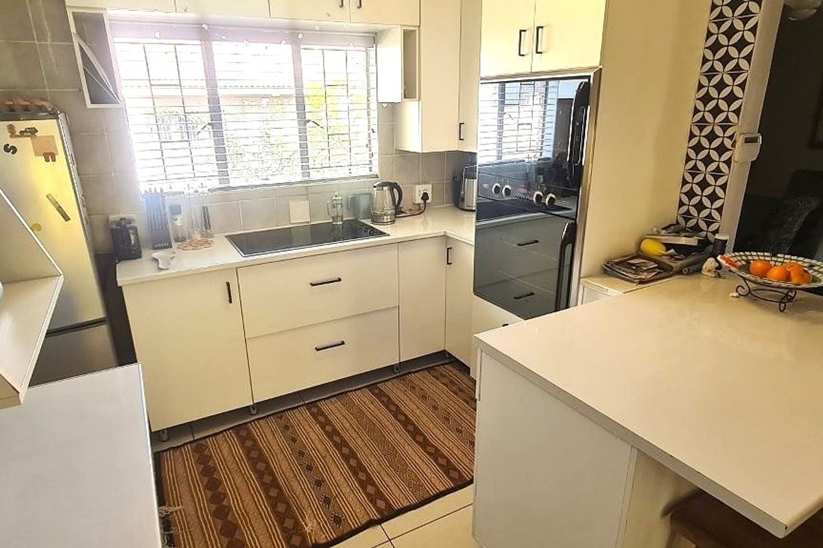 A functional kitchen featuring white cabinetry, integrated appliances, a breakfast bar, and a tiled backsplash, offering a clean and practical cooking space.