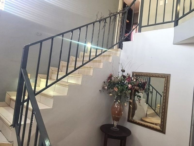 An entrance area featuring a tiled staircase with a black metal balustrade leading to an upper landing.
