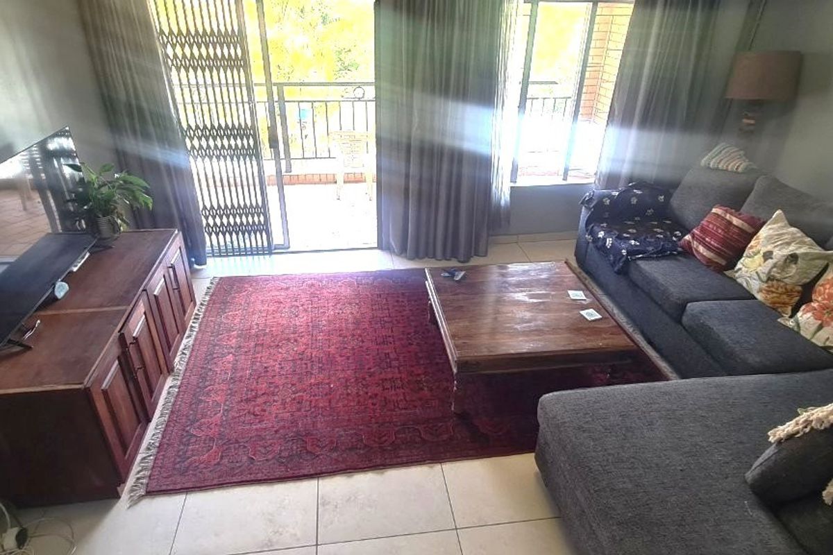 A living room featuring tiled flooring and a sliding glass door with a security gate, providing access to an outdoor area.