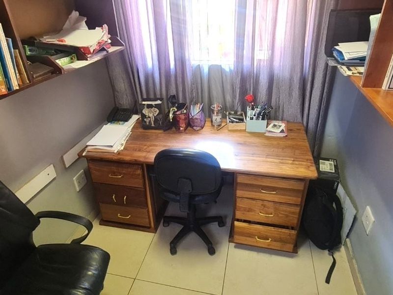 A compact home office featuring built-in wooden shelving and tiled flooring, providing a functional workspace.