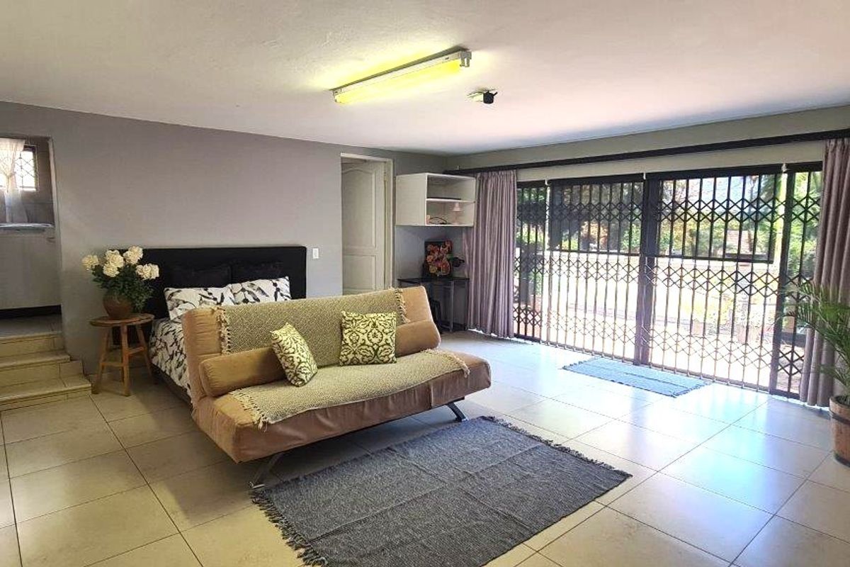 Spacious bedroom featuring tiled flooring, extensive built-in cupboards, and large sliding doors leading to the garden area.