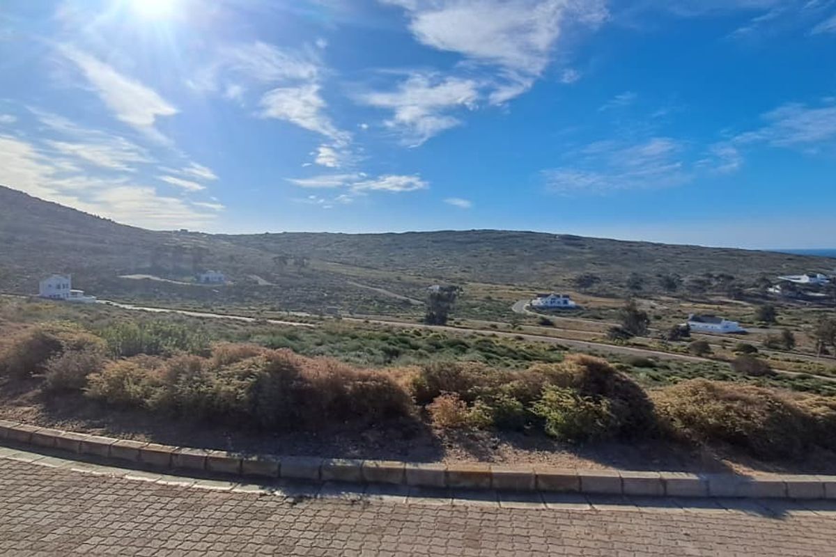 A wide-angle view of the surrounding coastal landscape and residential area, featuring natural vegetation and paved road infrastructure.