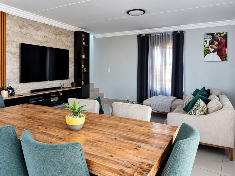 A modern open-plan living and dining area featuring a stylish stone-cladding feature wall, built-in shelving, and sleek tiled flooring throughout.
