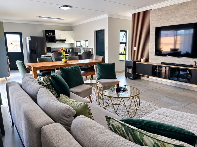 A modern, well-maintained open-plan living and kitchen area featuring tiled floors, a stylish timber-slat feature wall, and contemporary kitchen cabinetry.