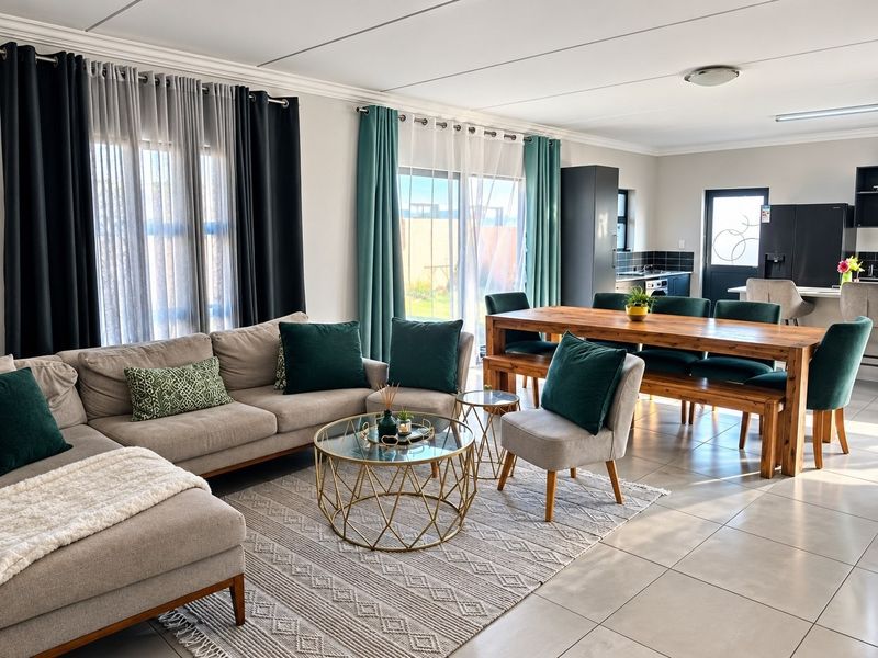 Spacious open-plan living and dining area featuring tiled floors, modern kitchen cabinetry, and large sliding doors providing natural light and garden access.