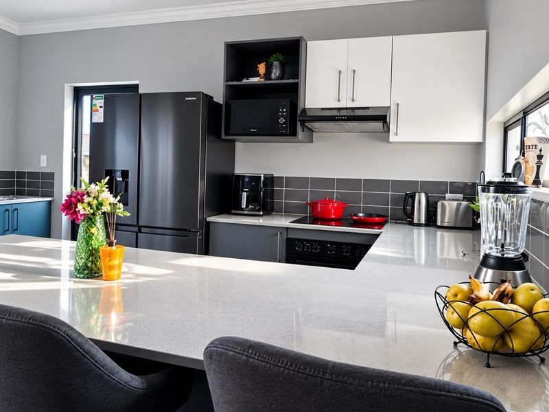 Modern kitchen featuring sleek cabinetry, quartz countertops, a tiled backsplash, and integrated appliances, offering a clean and functional culinary space.