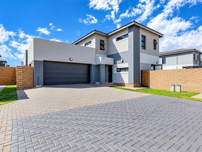 Modern double-storey residential home featuring a paved driveway, double garage, and clean contemporary architectural lines.